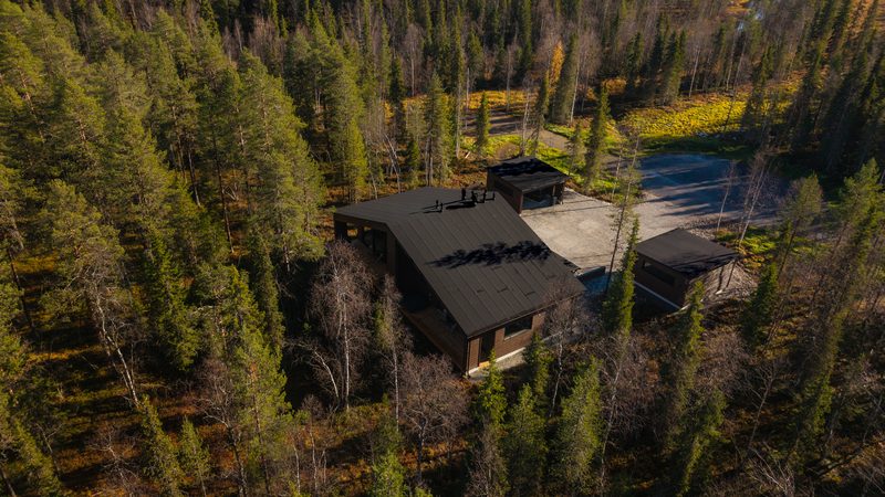 Villa Löhö from above and behind, showing the deck, the drive and the two carports among autumn birches.