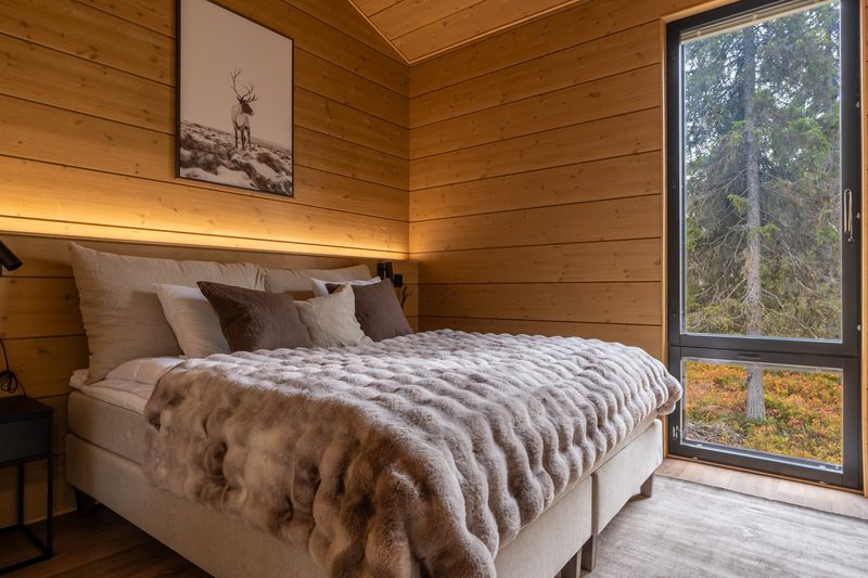 The main bedroom with a double bed, fur throw and a window looking straight into the forest.