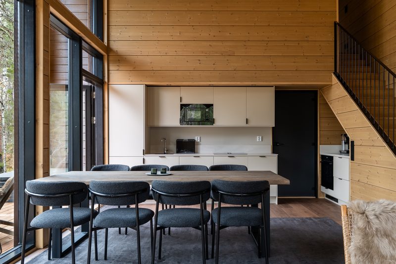 The kitchen across the dining table: pale cabinetry, integrated oven and eight chairs.