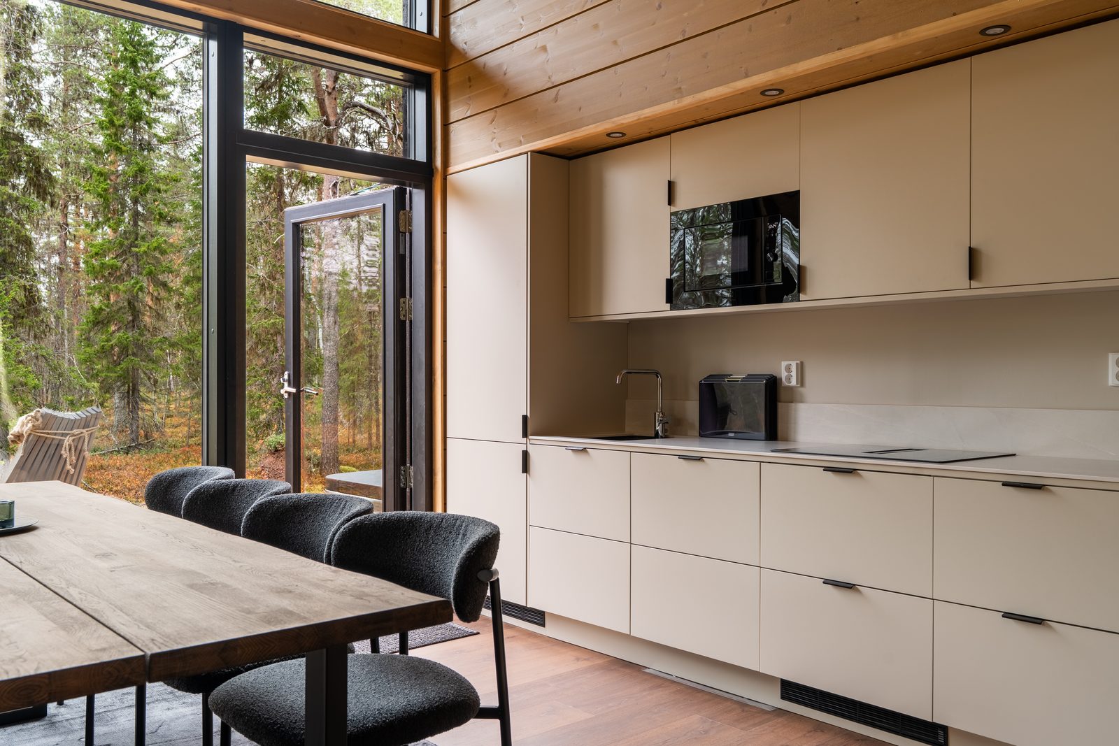 The kitchen: pale cabinetry along one wall, integrated oven and microwave, ceramic worktop, with the dining table in front of it.