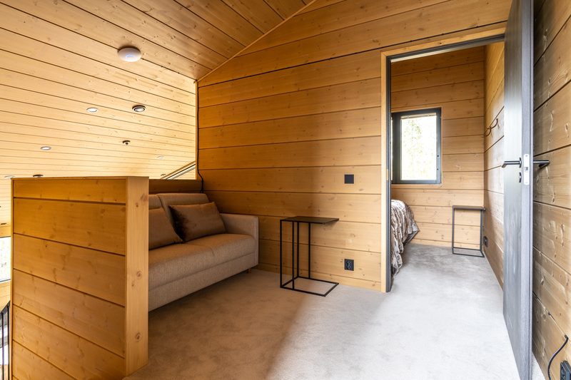 The upper landing with a sofa and a side table, and a bedroom doorway beyond.