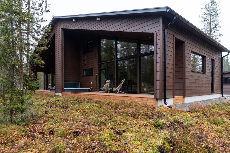 The back of Villa Löhö: a long covered deck with a jacuzzi and chairs, facing open forest.