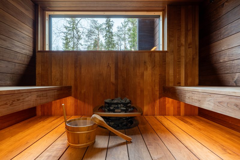 The sauna with thermo-aspen benches, a bucket and ladle, and a window at bench height.