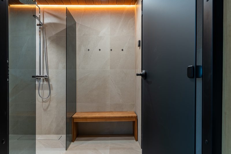 The second rain shower in the washroom, with a timber bench and the door through to the living area.